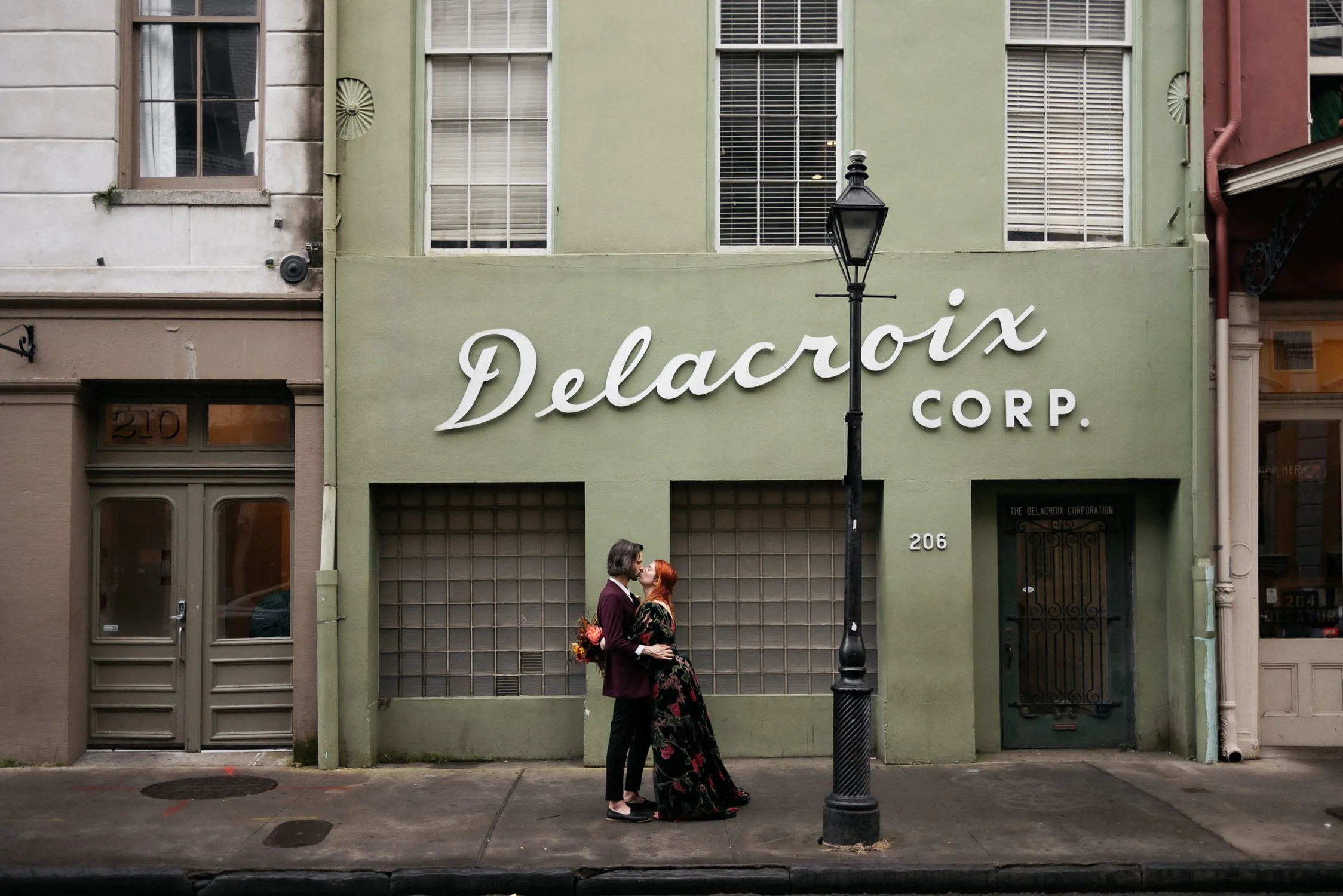 In an evocative city scene by Jean Laurent Gaudy, acclaimed in the Top Wedding Photographers of 2024, a couple shares a romantic embrace in front of the vintage Delacroix Corp. building, a moment of love captured amidst the urban charm of New Orleans.