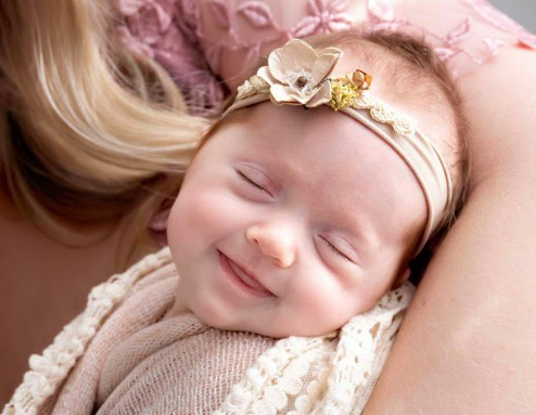 Smiling baby in her mother's arms right after a breastfeeding session